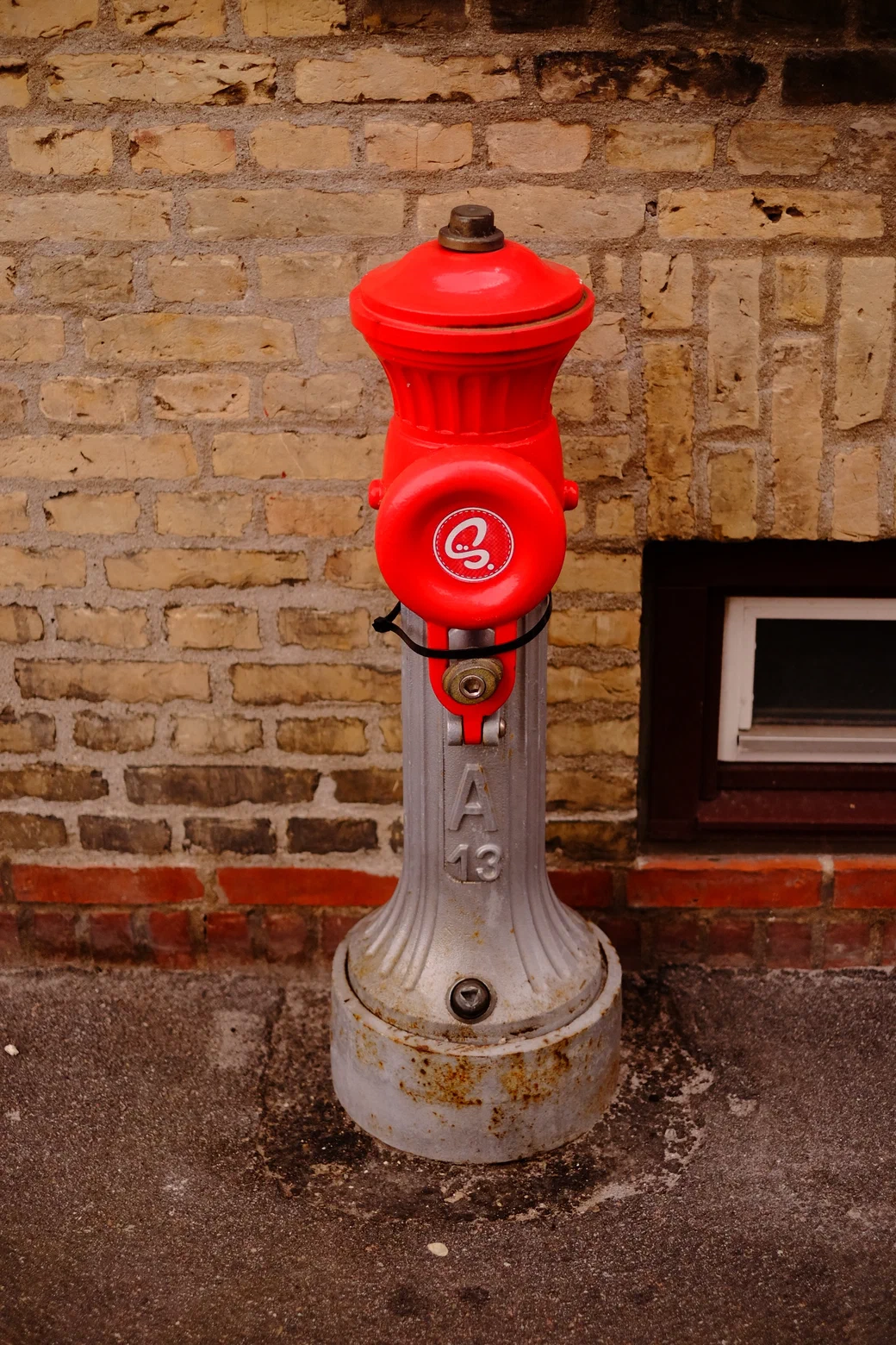 a red fire hydrant against a brick wall