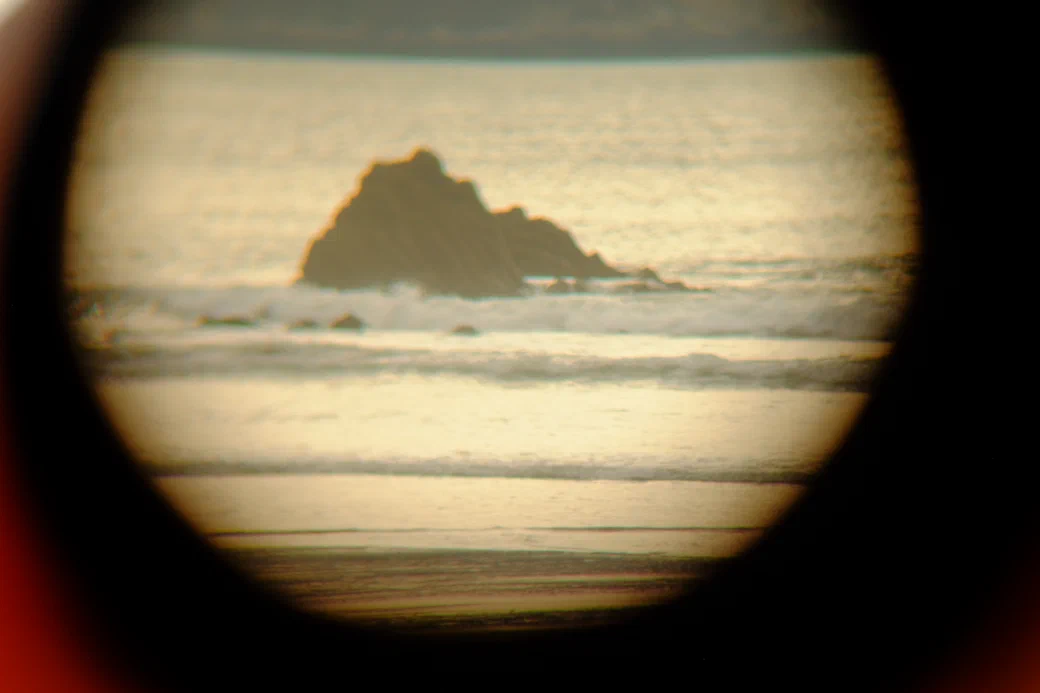a sea rock in the surf, through a lens