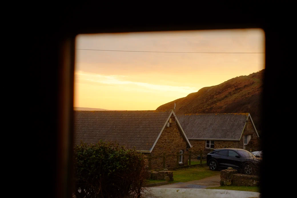 sunset over stone cottages, through a window